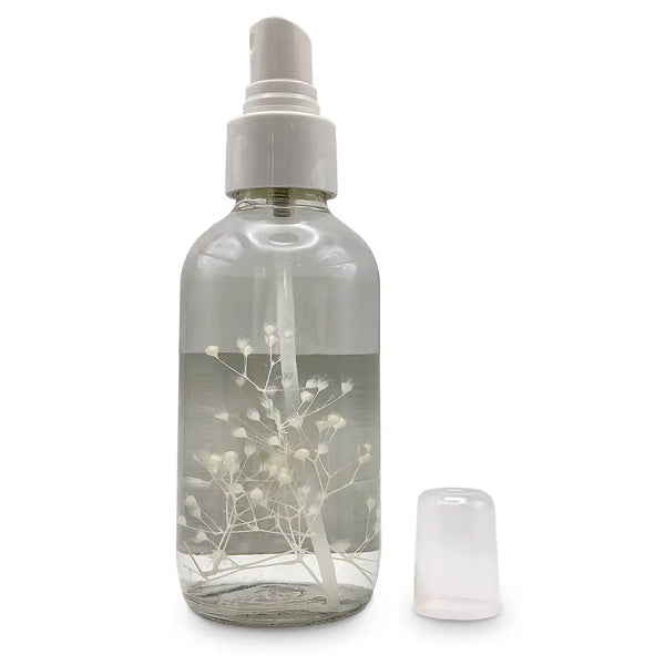 Clear spray bottle with white flower/plant inside and white label.