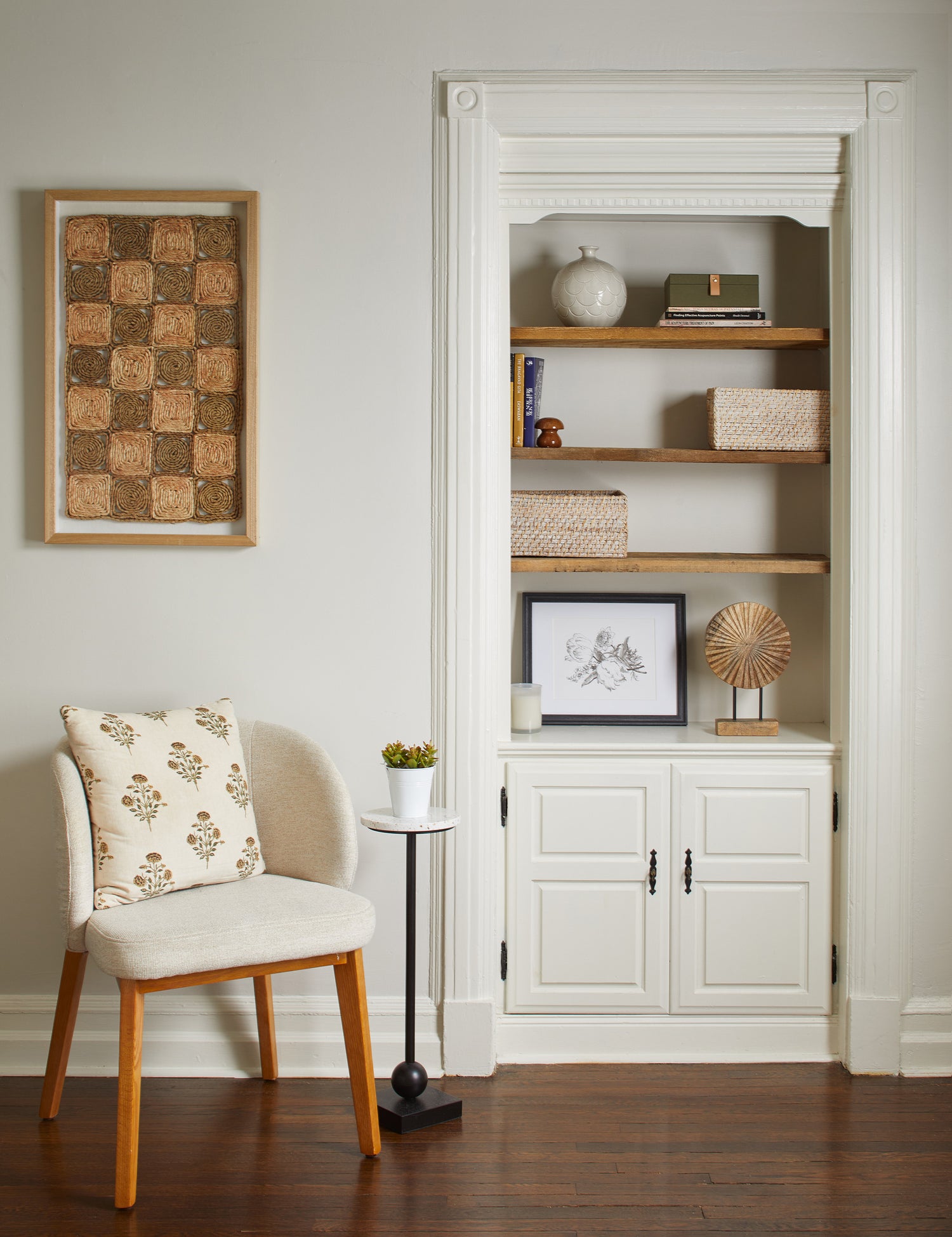 A nook area of a Jennifer Layne treatment room containing a built-in bookcase and cabinet, a chair, and other decorative elements