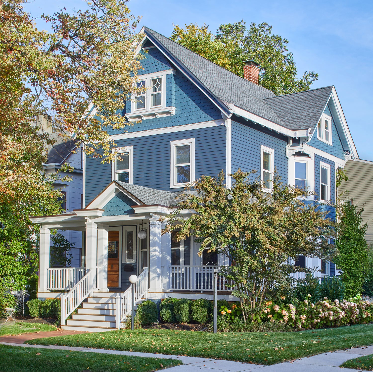 The Jennifer Layne office -- a blue 3-story house with white trim and a porch, surrounded by trees and flowers