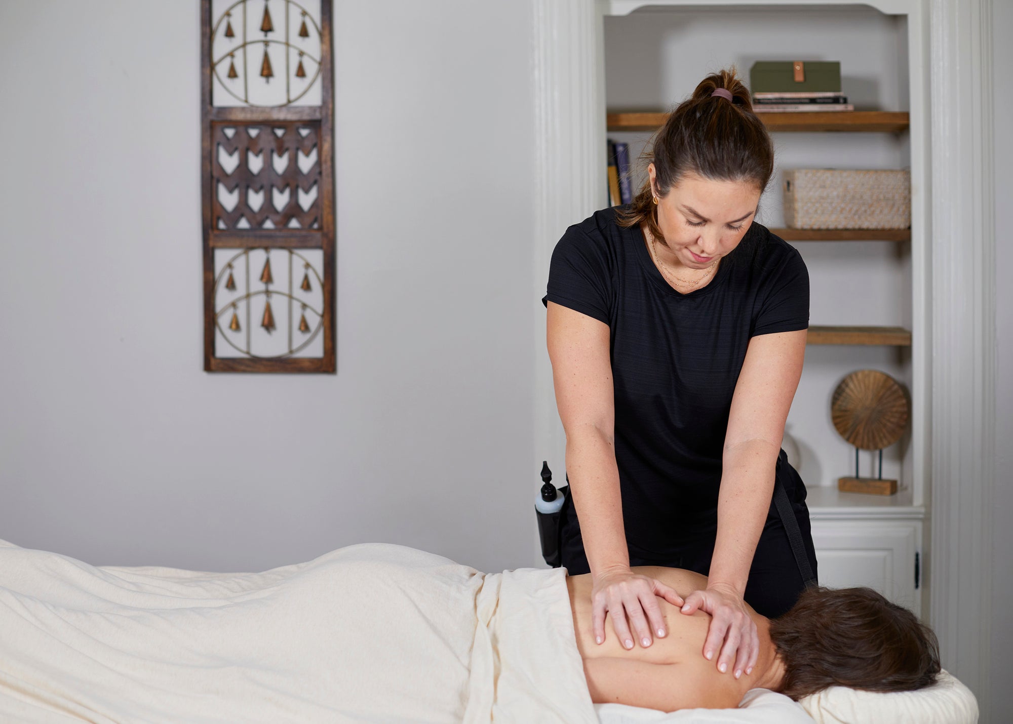 Magda Karpowicz performing massage on a patient's back in a treatment room.