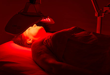 A patient receiving red light therapy in a dark treatment room.