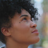 A woman's face looking up at the sky with a content expression.